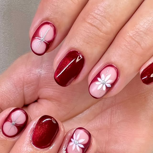 Tiefrotes Nageldesign mit weißen Blütenranken